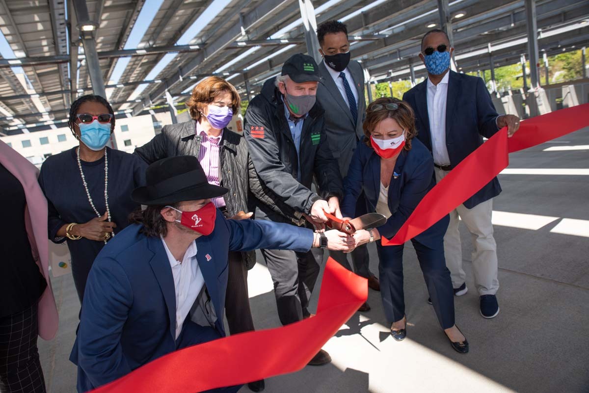 Principals cutting the ribbon at the Children's Research and Innovation Campus parking lot solar canopy opening.