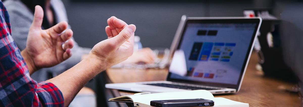 Closeup of a person's hands gesturing in front of a laptop.