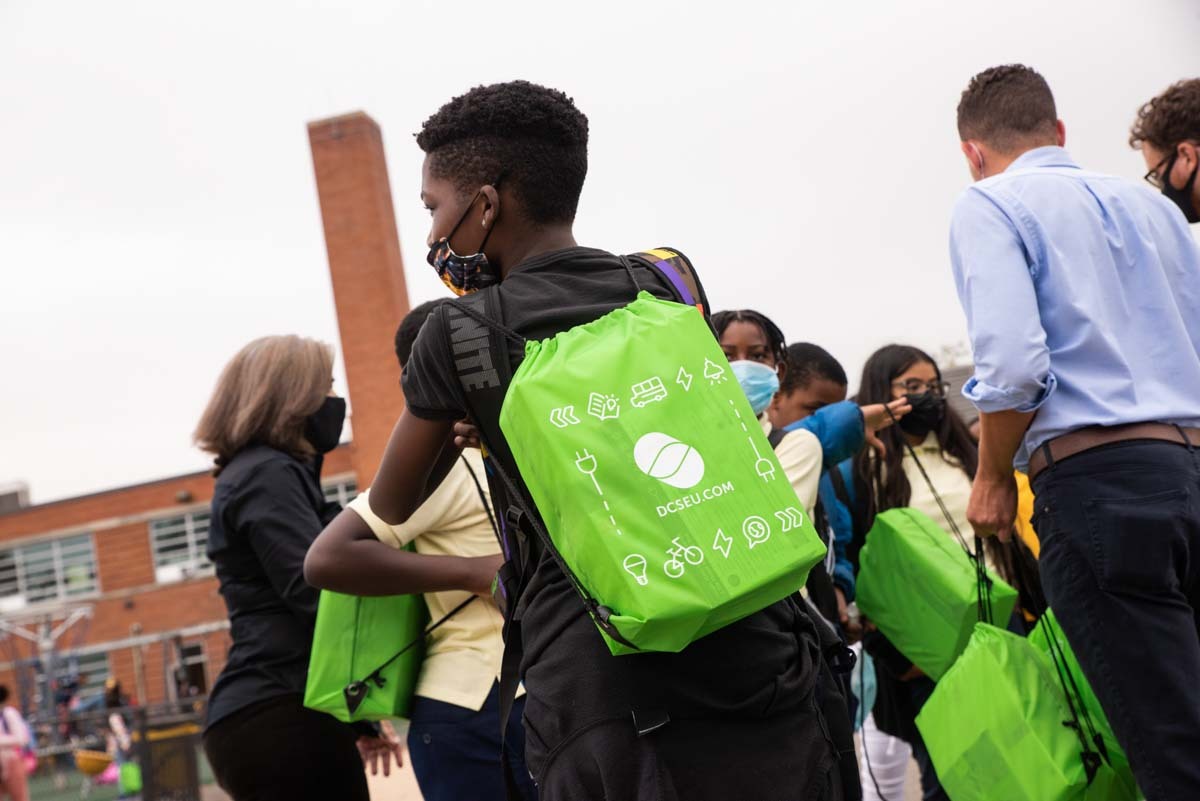 Young student puts on DCSEU bag with efficient LED lighting kits inside.