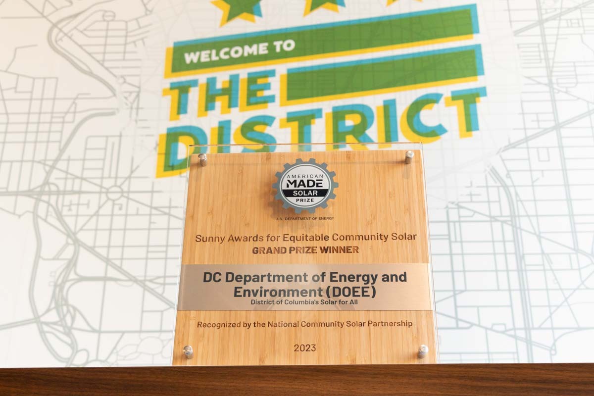 Sunny Award plaque in front of a sign that says, welcome to the District.
