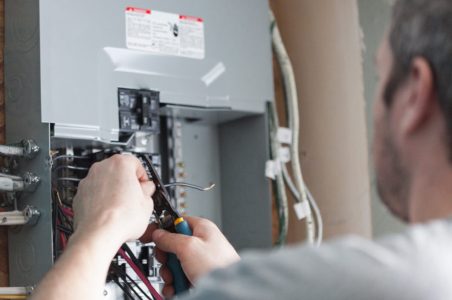 Close up of an electrician working on the wiring in an electric panel box.