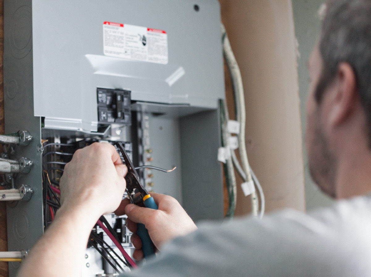 Close up of an electrician working on the wiring in an electric panel box.