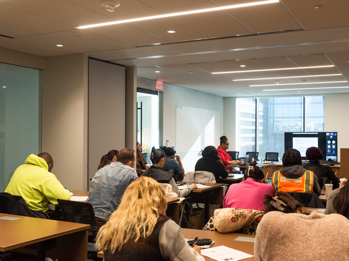 Adult students in an office classroom setting watching a training video.