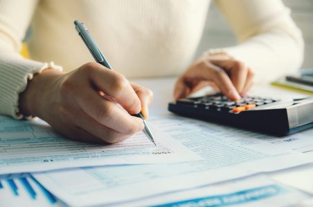 Close up of a person's hands filling out and IRS tax document.