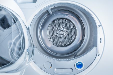 A view inside the metallic drum of a front-loading heat pump clothes dryer.