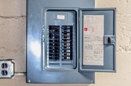 Direct flash picture of a gray electrical panel with the door open and circuit breaker visible.