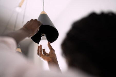 Person screwing in a LED lightbulb into a pendant light fixture.