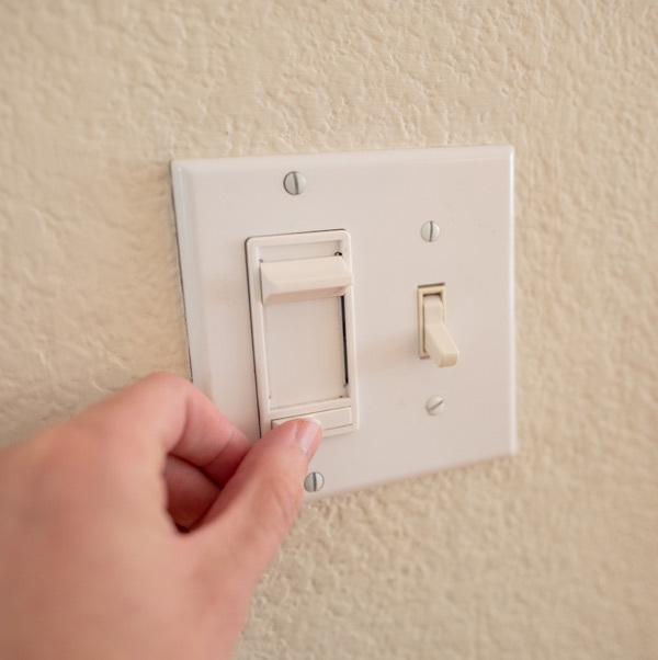 Closeup of a person adjust a dimmable light switch.