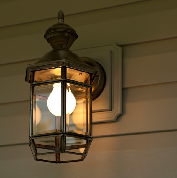 Closeup of an outdoor wall lantern fixture mounted on the front of a house.