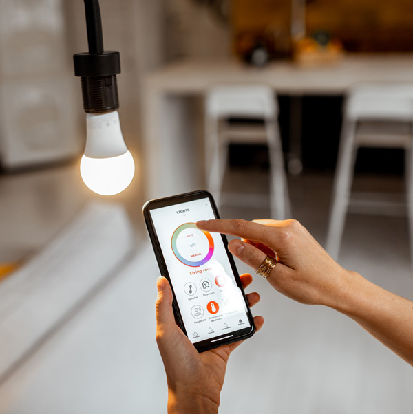 Closeup of a person using a smart phone app to control a plugged-in smart LED bulb.