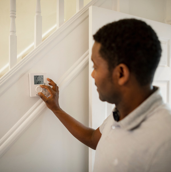 A person changing the temperature on a programmable thermostat.